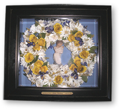 shadow box with preserved wreath of flowers and prayer figurine